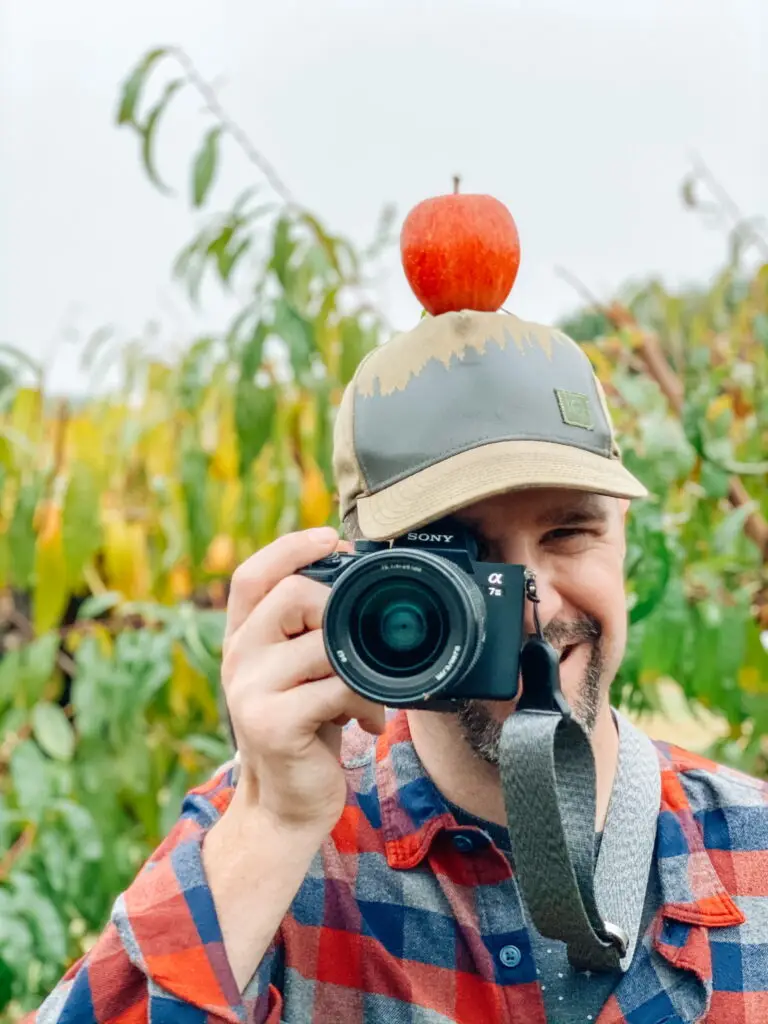 Joel holding a Sony A7iii camera with an apple on his head