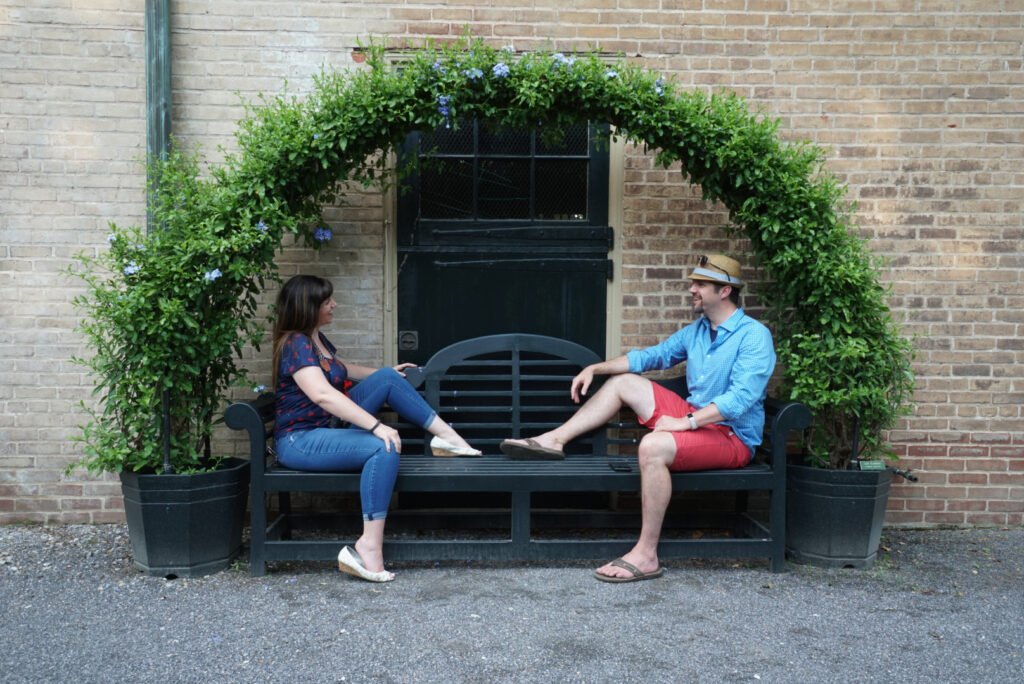 Joel and Christine on a bench under a shrub